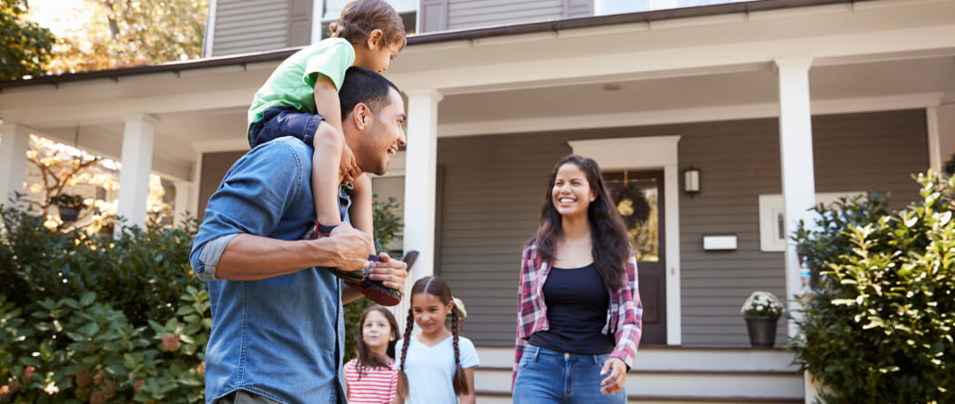 A young family playing together outside a large home