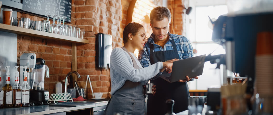 Two cafe workers looking at a laptop