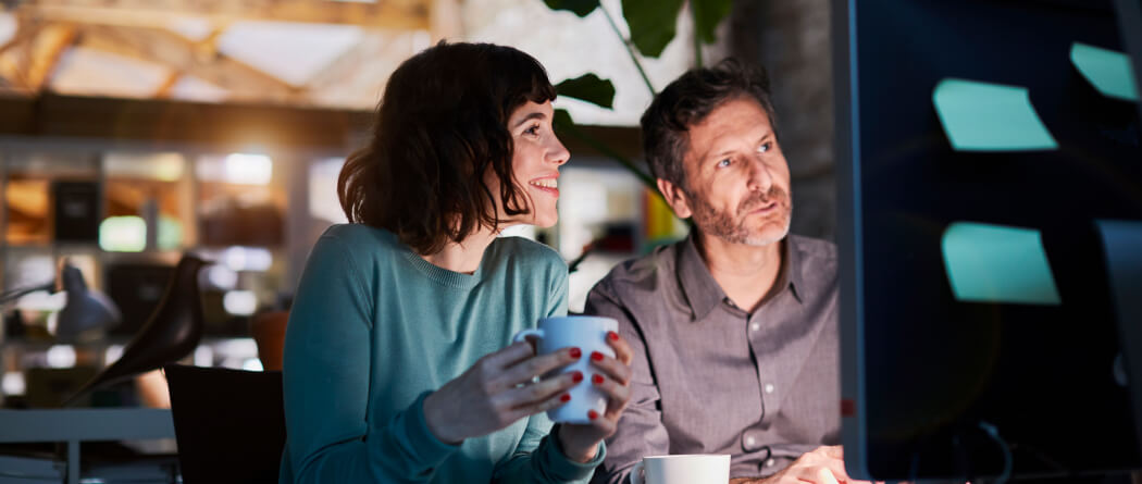 Two coworkers looking at a computer monitor 